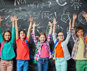 Happy school kids at the classroom chalkboard