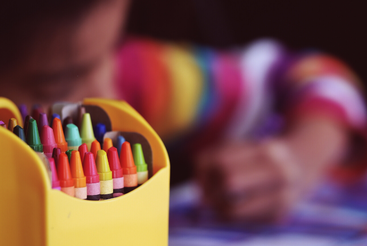 A young child colouring with crayons