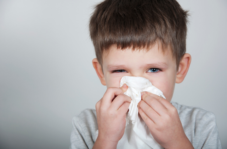 School aged boy blowing nose stopping spread of illness at school