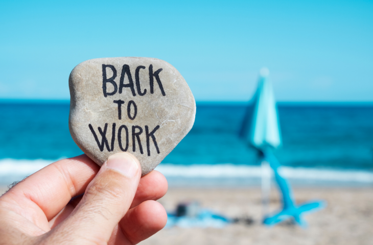 Man at Beach holding rock that says back to work