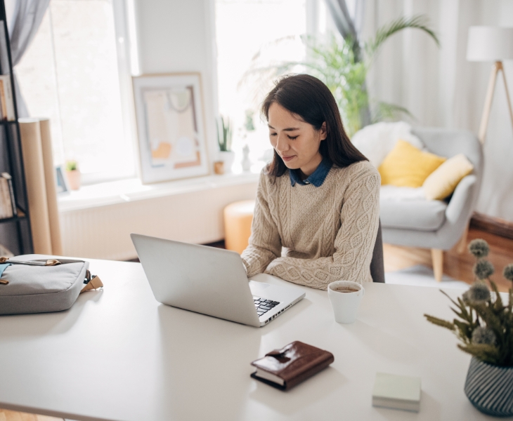 A lady sitting and working from home on a a laptop