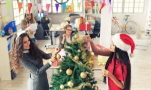 2 girls decorating Christmas tree in the office