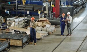 Three people standing in warehouse and working