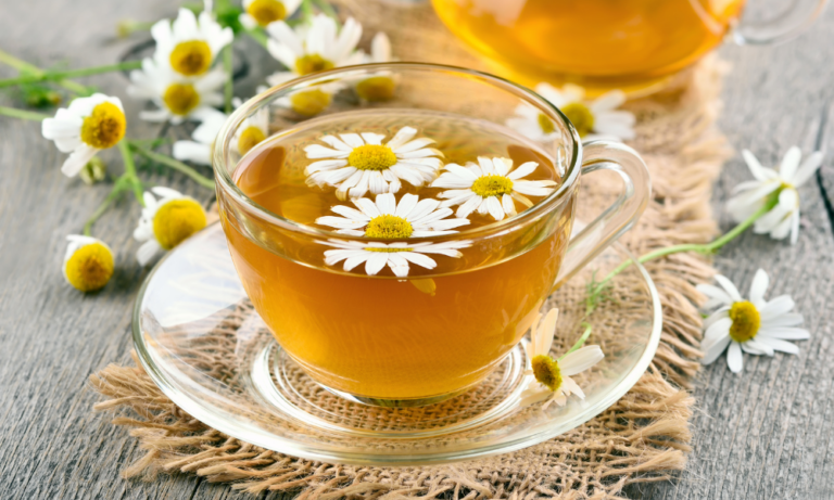 Herbal Chamomile tea in transparent cup with flowers sprinkled