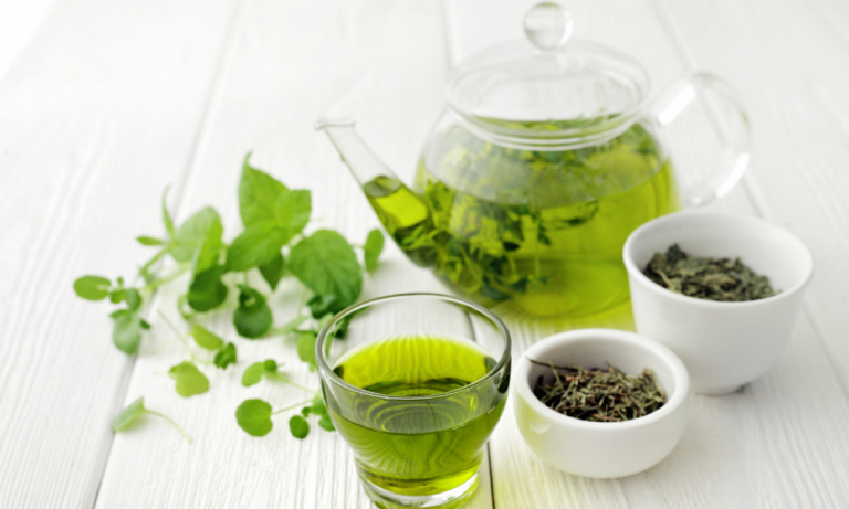 Healthy green tea in a cup with green tea leaves around