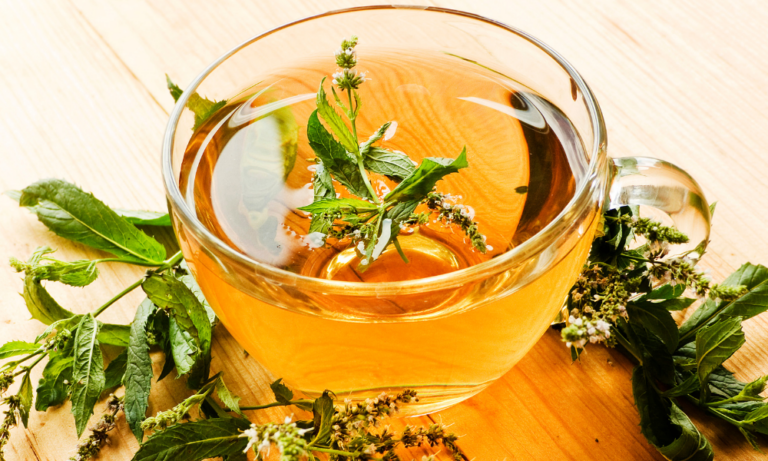 Cup of pepper tea with leaves sprinkled on top