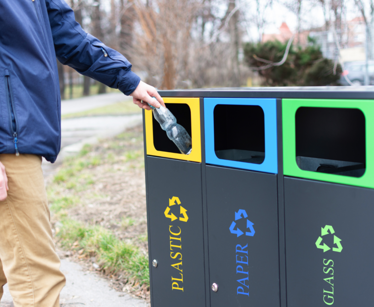 Man Throwing Plastic Bottle in Segregated Trash Bins